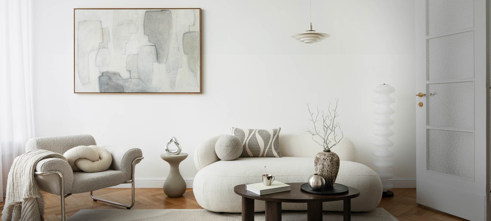 Modern living room with a white sofa, armchair, and abstract art on the wall.