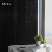 GoDear Design Black textured curtain filtering light in a room with a table and plants.