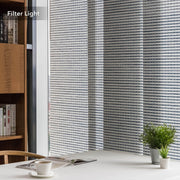 GoDear Striped window blinds filtering light in a room with a bookshelf and plant.