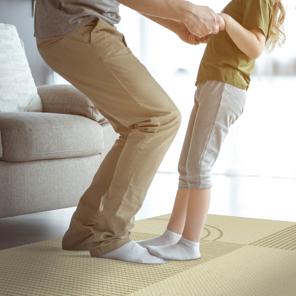 Person and child holding hands on a carpeted floor in a living room.