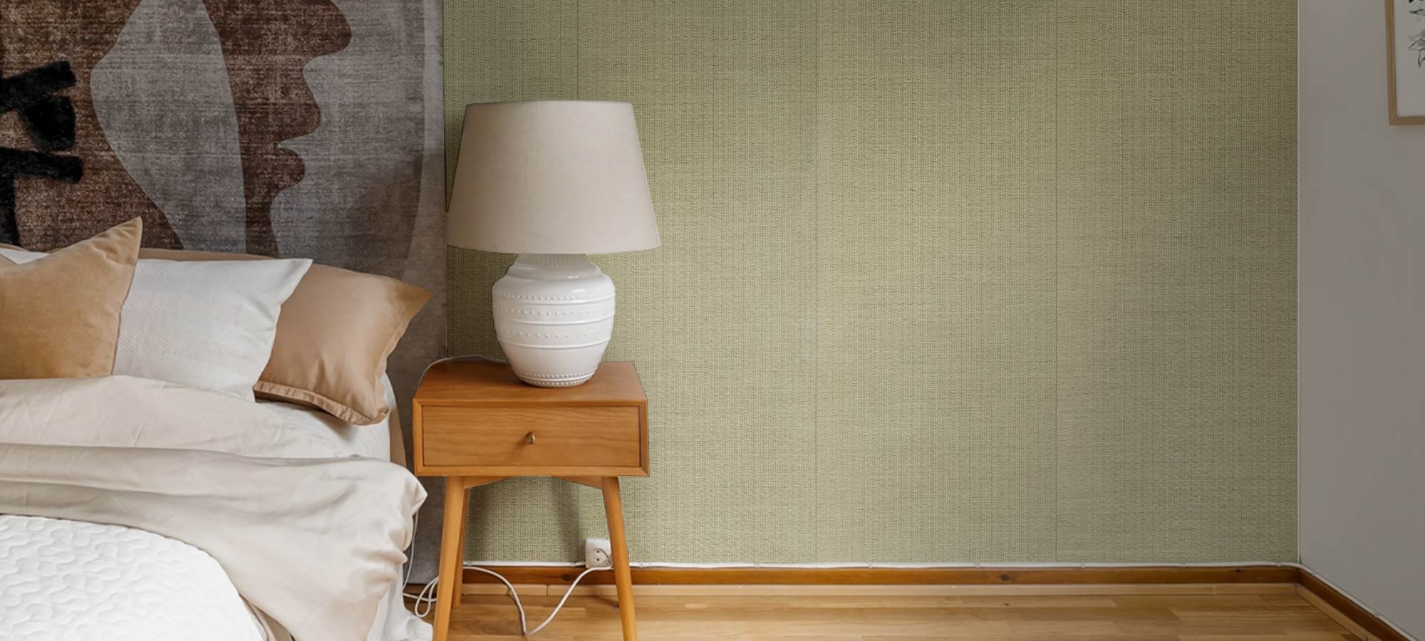 Cozy bedroom with neutral wall texture, wooden nightstand, and ceramic lamp.