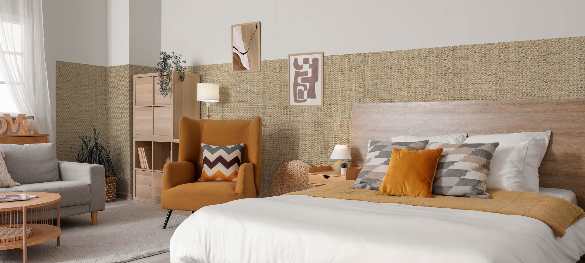 Modern bedroom interior with woven accent wall, wooden headboard, mustard yellow armchair, and layered pillows in neutral tones.
