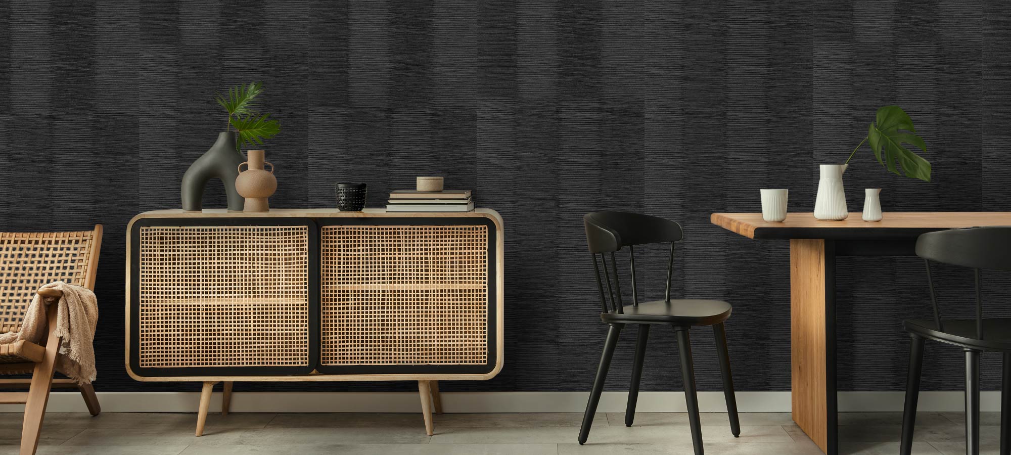 Vivid modern dining room featuring dark textured wall, rattan cabinet, wooden dining table, and black chairs with minimalist decor.