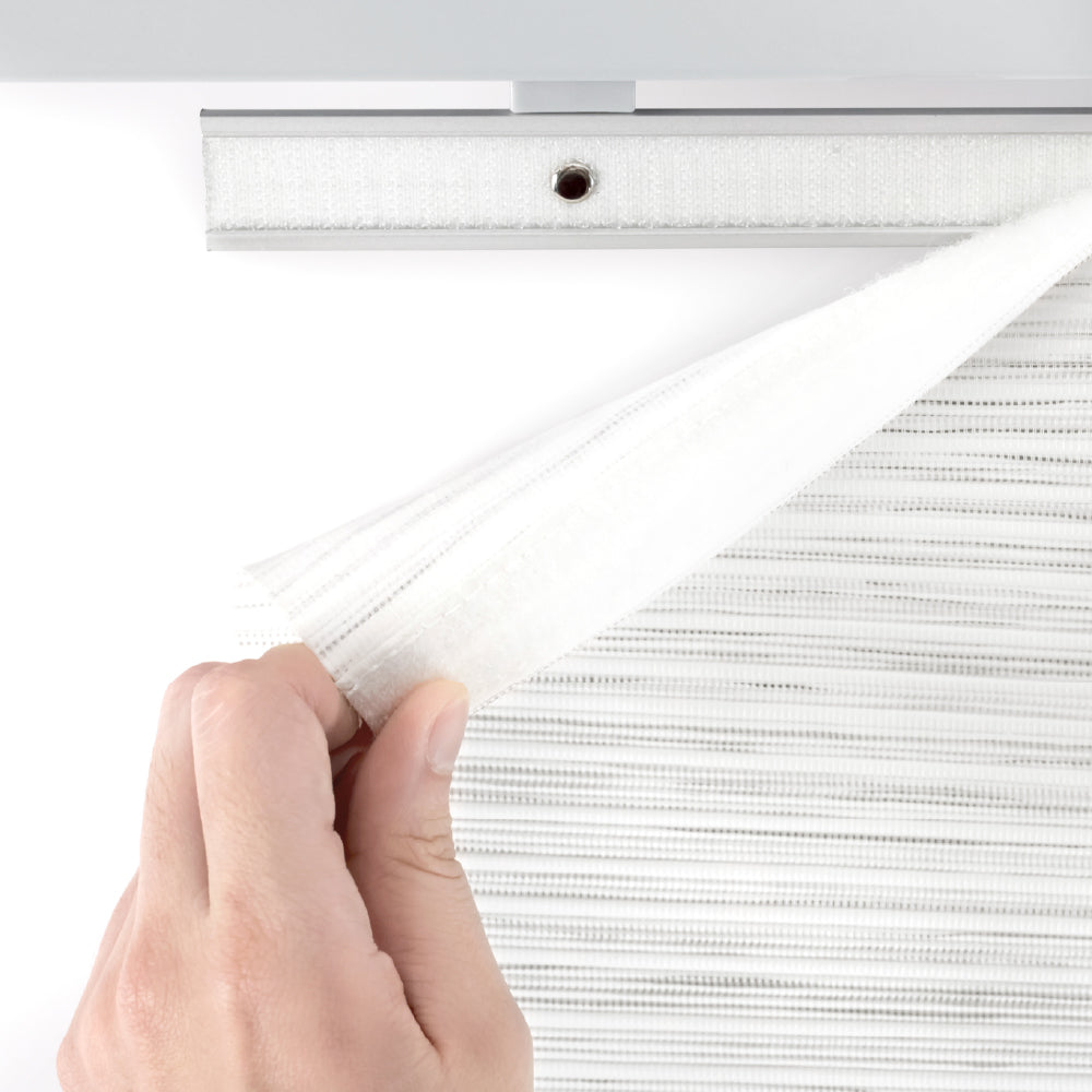 Hand pulling a white panel fabric with a metal track against a light gray background
