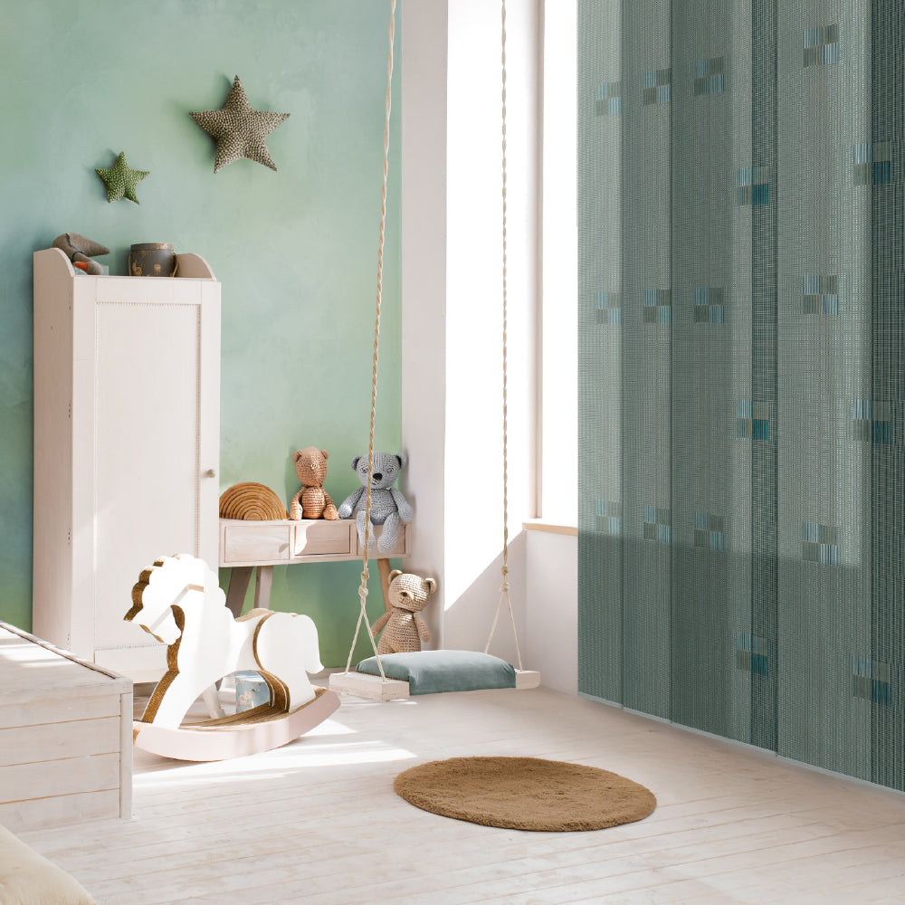 Children's room with green walls, toys,  sheer panel blinds and a rocking horse.