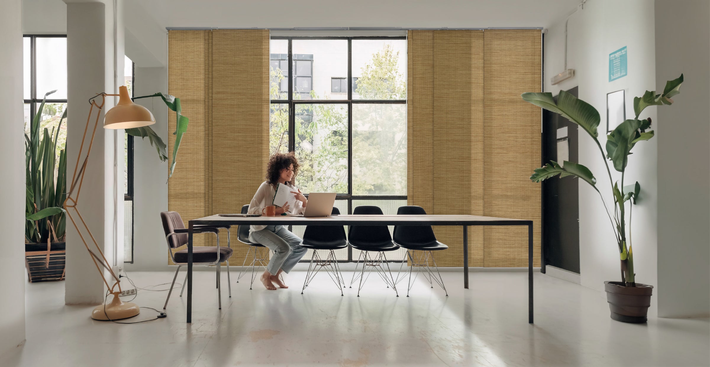 GoDear Design_Modern interior with a person sitting at a table, large windows, and decorative plants.