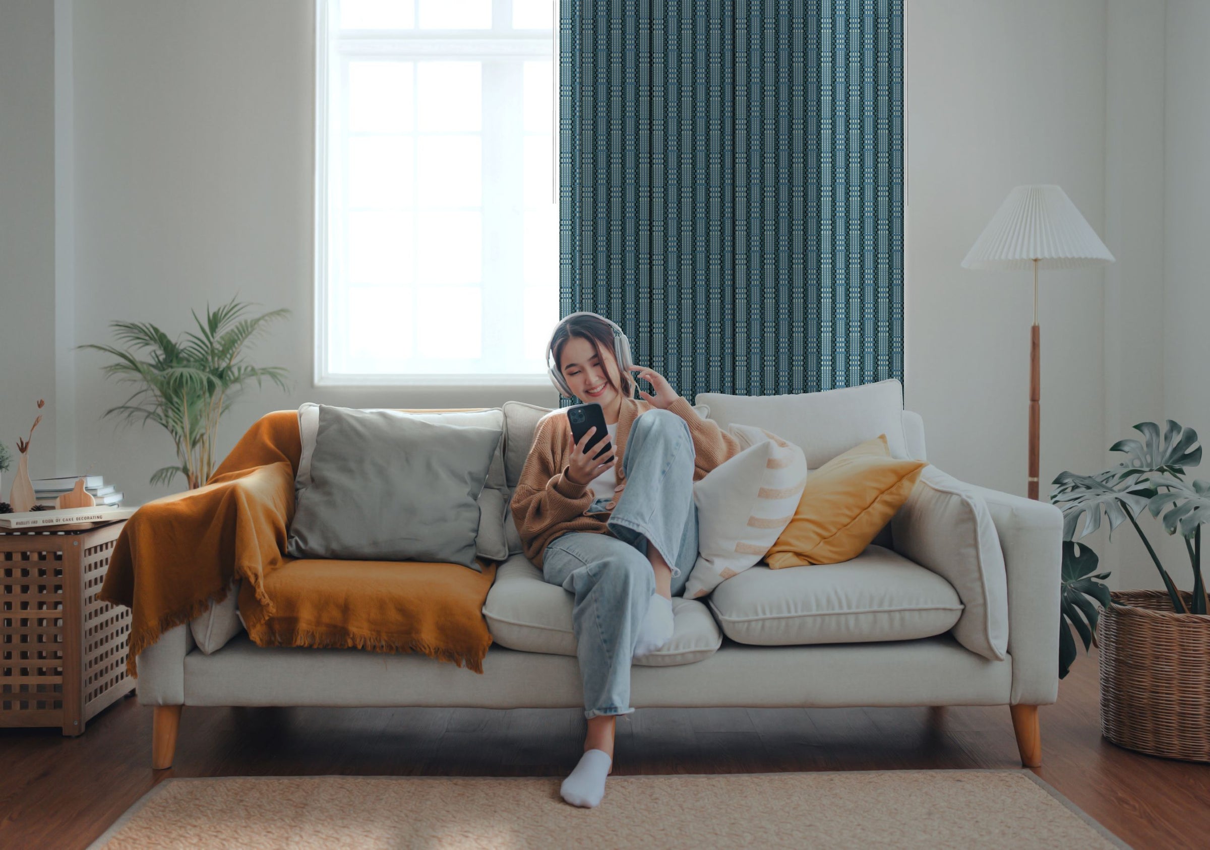 GoDear Design_Person sitting on a white sofa with a yellow blanket, using a phone in a cozy living room.