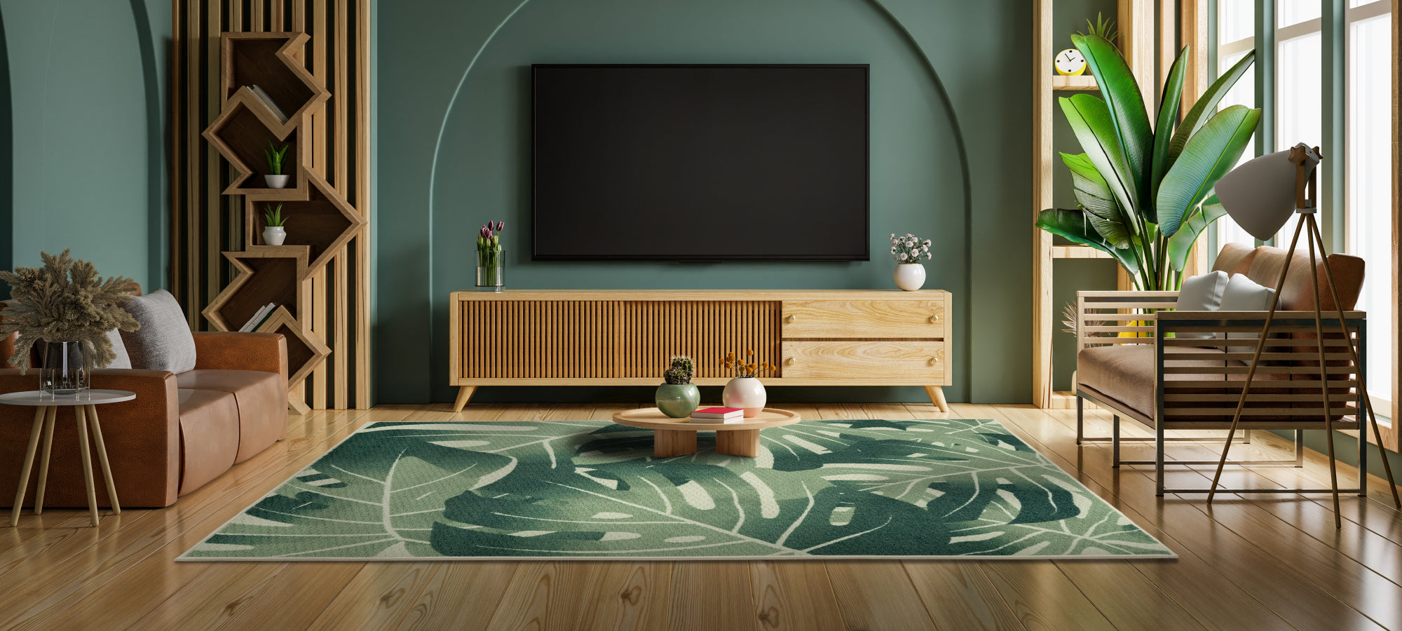 The Palm Leaves area rug with dark green leaf motifs placed in a modern living room with white sofas and wood furnishings, complementing the natural light and mountain scenery visible through large glass doors.