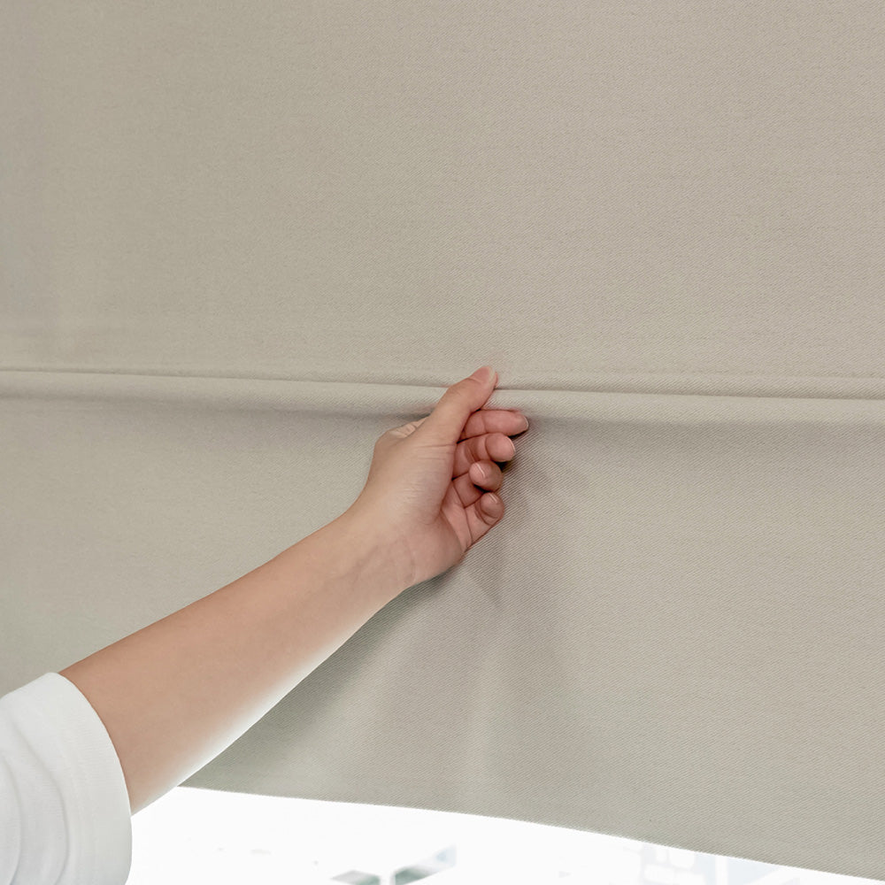 GoDear Design Hand pulling a beige roller blind