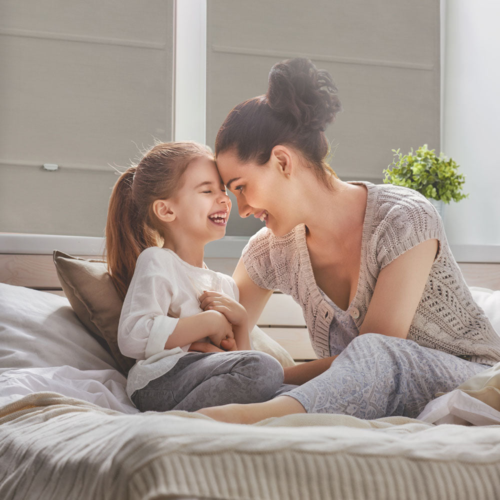 GoDear Design_Woman and child laughing together on a bed in a bright room